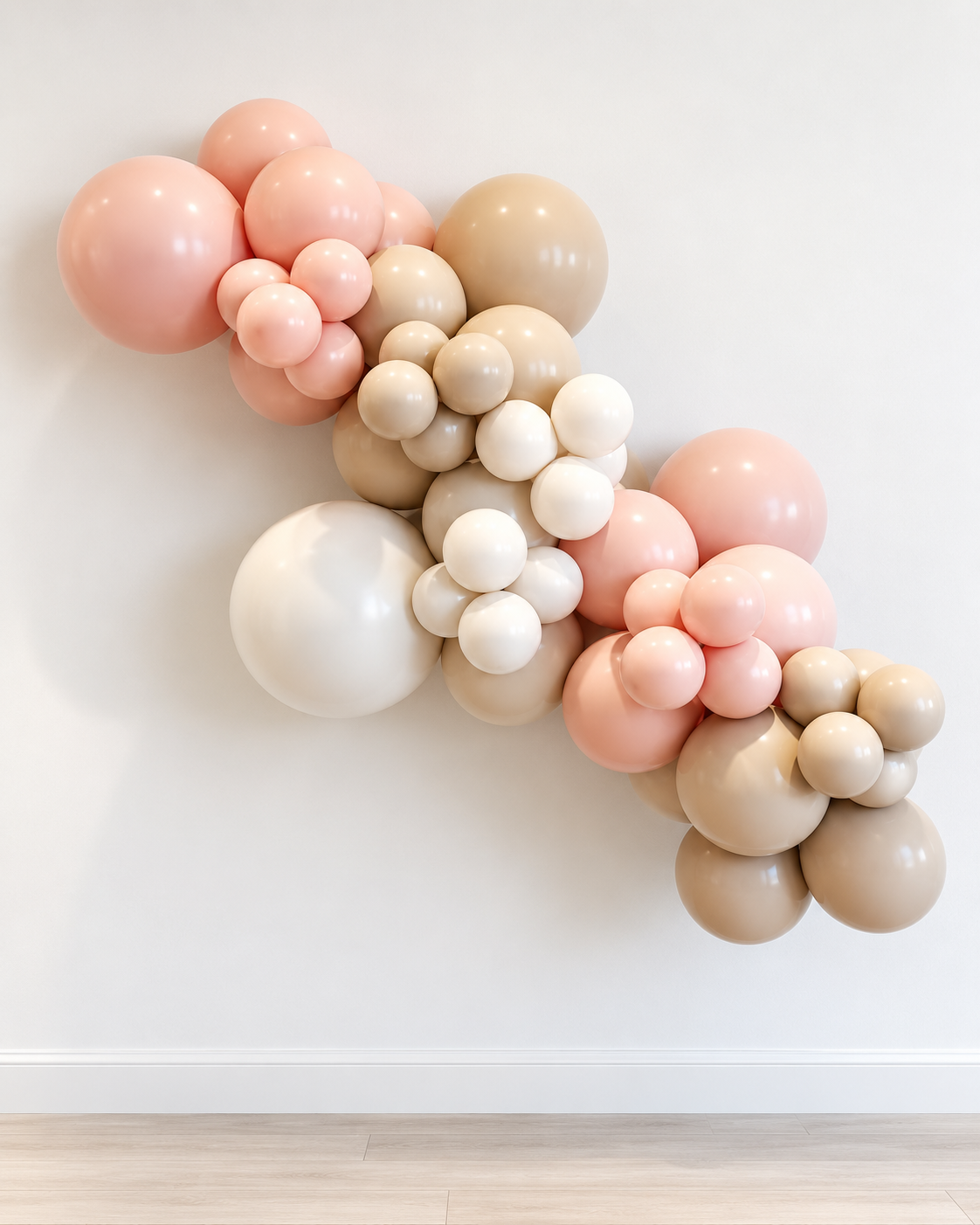 Blush pink, peach, sand and ivory organic balloon garland hanging on a wall